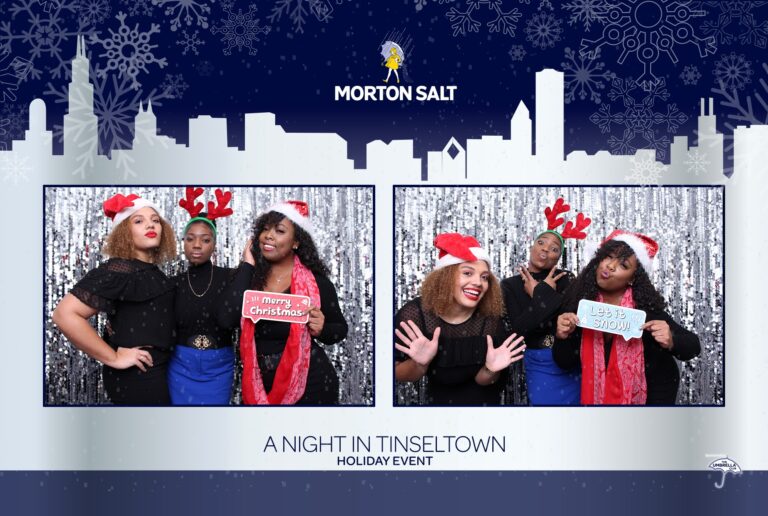 Three people pose in festive attire at a Morton holiday party photo booth. They wear red and white accessories, with two holding signs that say Merry Christmas and Let it snow. A snowy cityscape and the Morton Salt logo are visible in the background, capturing the holiday spirit perfectly.