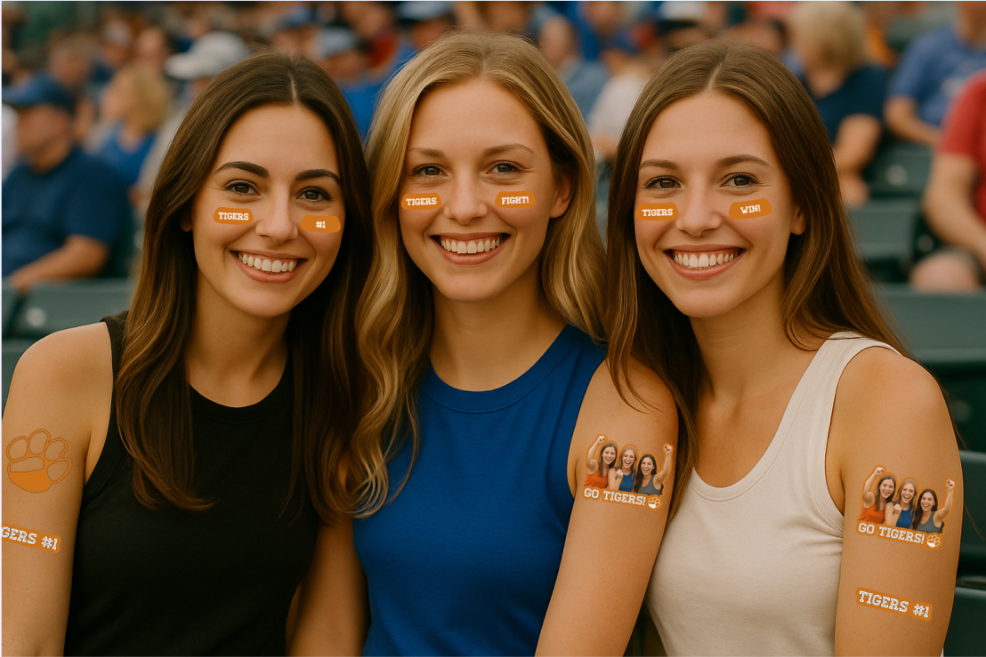 Three young women sitting together in a stadium, smiling, with face stickers and temporary tattoos showing support for the Tigers team.