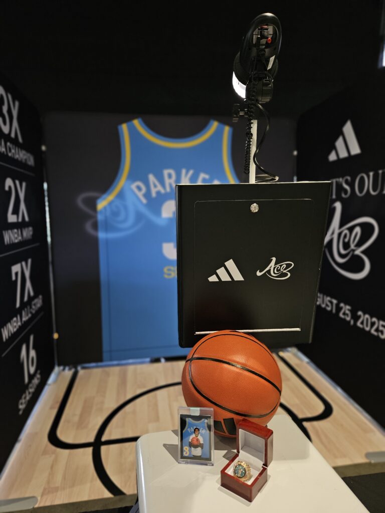 A basketball-themed display with a jersey, basketball, trading card, and ring under a spotlight—perfect for Chicago Photo Booth Rental brand activations with stats and awards on the backdrop.