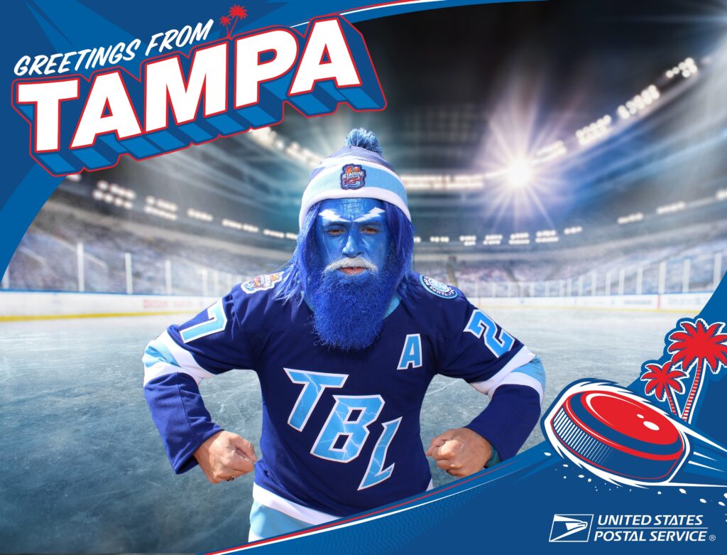 A person in blue Tampa Bay Lightning gear and face paint poses in a hockey arena, with Greetings from Tampa, USPS logos, and an AI Photo Booth Las Vegas display in the frame.