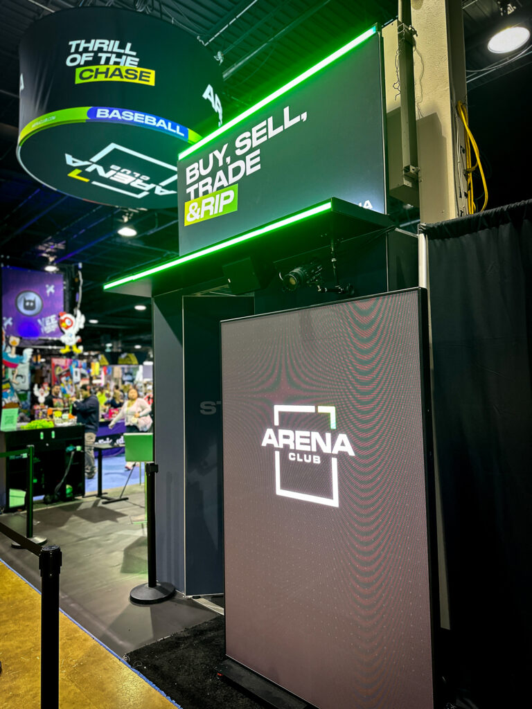 A booth at an event showcases ARENA CLUB with colorful lighting, perfect for Sports Marketing Activation and dynamic Brand Activation Ideas in a lively atmosphere.