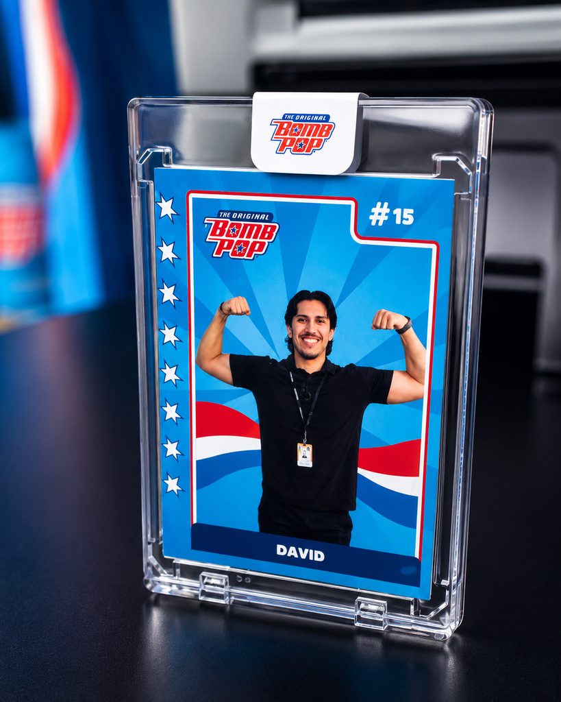 A man in a black shirt flexes on a blue Arena Club trading card labeled #15 David, showcased in a clear holder—perfect for Custom Trading Cards fans or Trading Card Photo Booth Rental events.